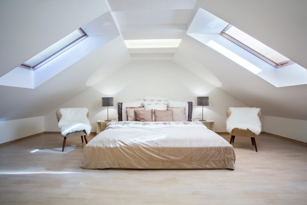 A bed with two chairs and side tables in an attic.