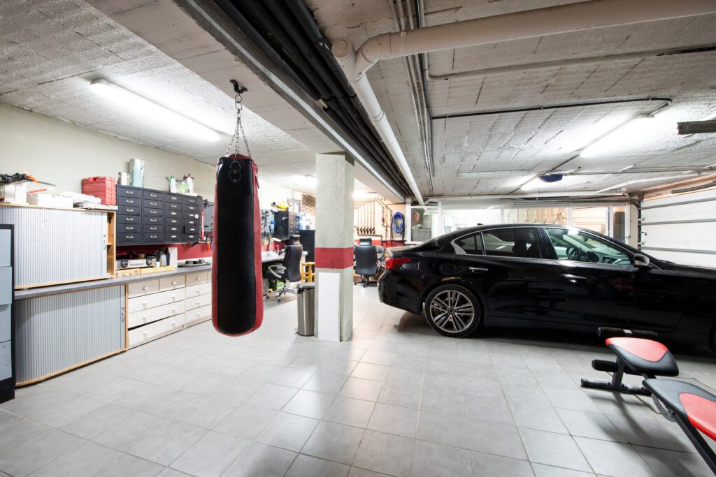 A punching bag, wood workshop, and car inside a detached garage.
